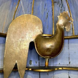 Coppery metal weathervane in the shape of a cockerel.