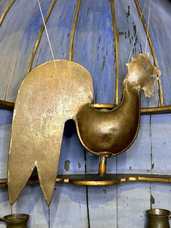 Coppery metal weathervane in the shape of a cockerel.
