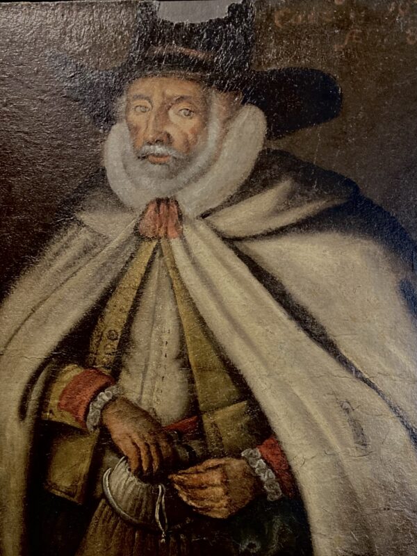 Painted portrait of person wearing large hat and cloak.
