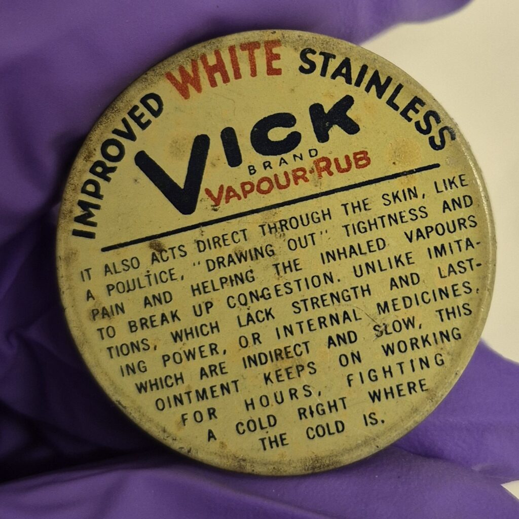 Circular tin with red and black writing. In an arc around the top of the text reads 'Improved White Stainless'. Underneath arc of text reads 'Vick brand Vapour-Rub' below this is small print of instructions.