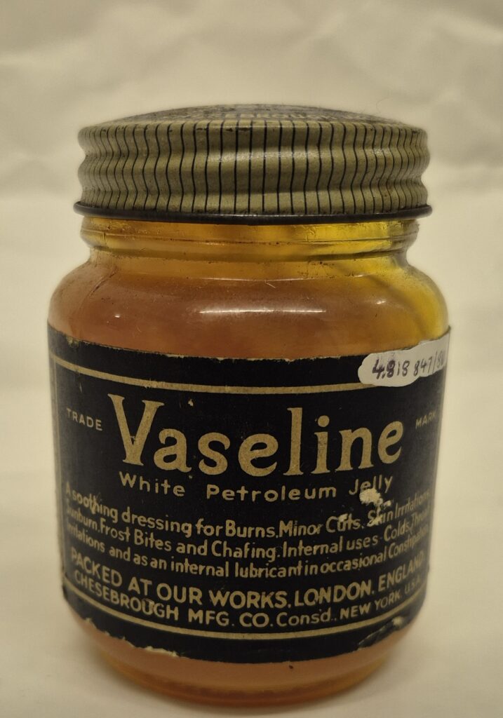 Light brown glass jar with cream and black pinstriped lid. Navy blue lable with cream text which reads 'Vaseline white petroleum jelly along with further, smaller text underneath.