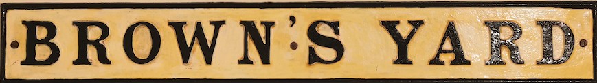 Cream enamel road sign with black capitalised writing which reads BROWN'S YARD.