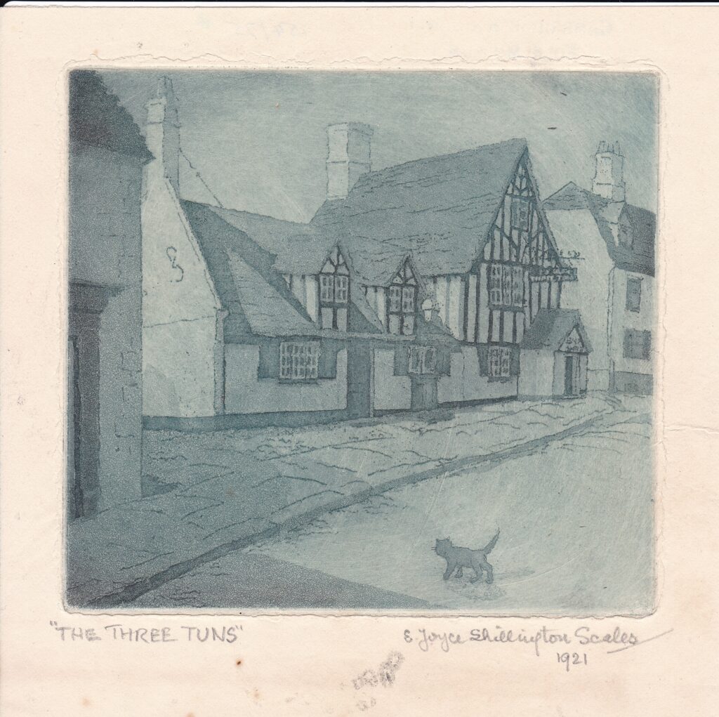 Greyscale watercolour of a street. A Tudor-style features with a black cat walking across the road toward the pavement . in the boarder of the image their is handwritten text reading 'The Three Tuns' E Joyce Shillington Scales, 1921.