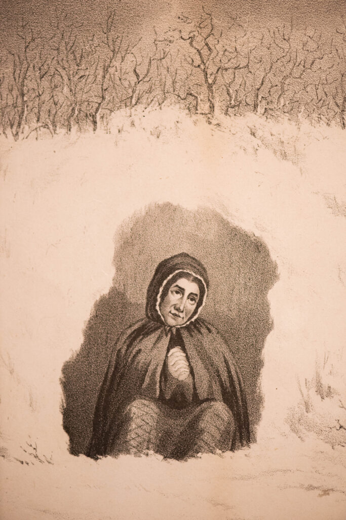 Sepia etching of a woman, Elizabeth Woodcock depicted in a cavern under the snow. She wears a hooded cape, and she is seated with her knees to her chest and her hands clasped in prayer. The snow is represented by negative space defined by a row of trees at the top of the drawing and Elizabeth and her cavernous surroundings shaded in the centre.