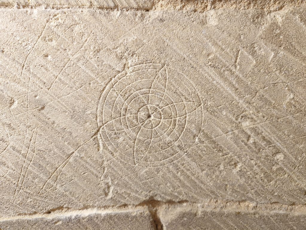 White plaster with a daisy shape formed from the plaster work. Circles radiate from the centre of the daisy getting increasingly larger to encircle the whole design.